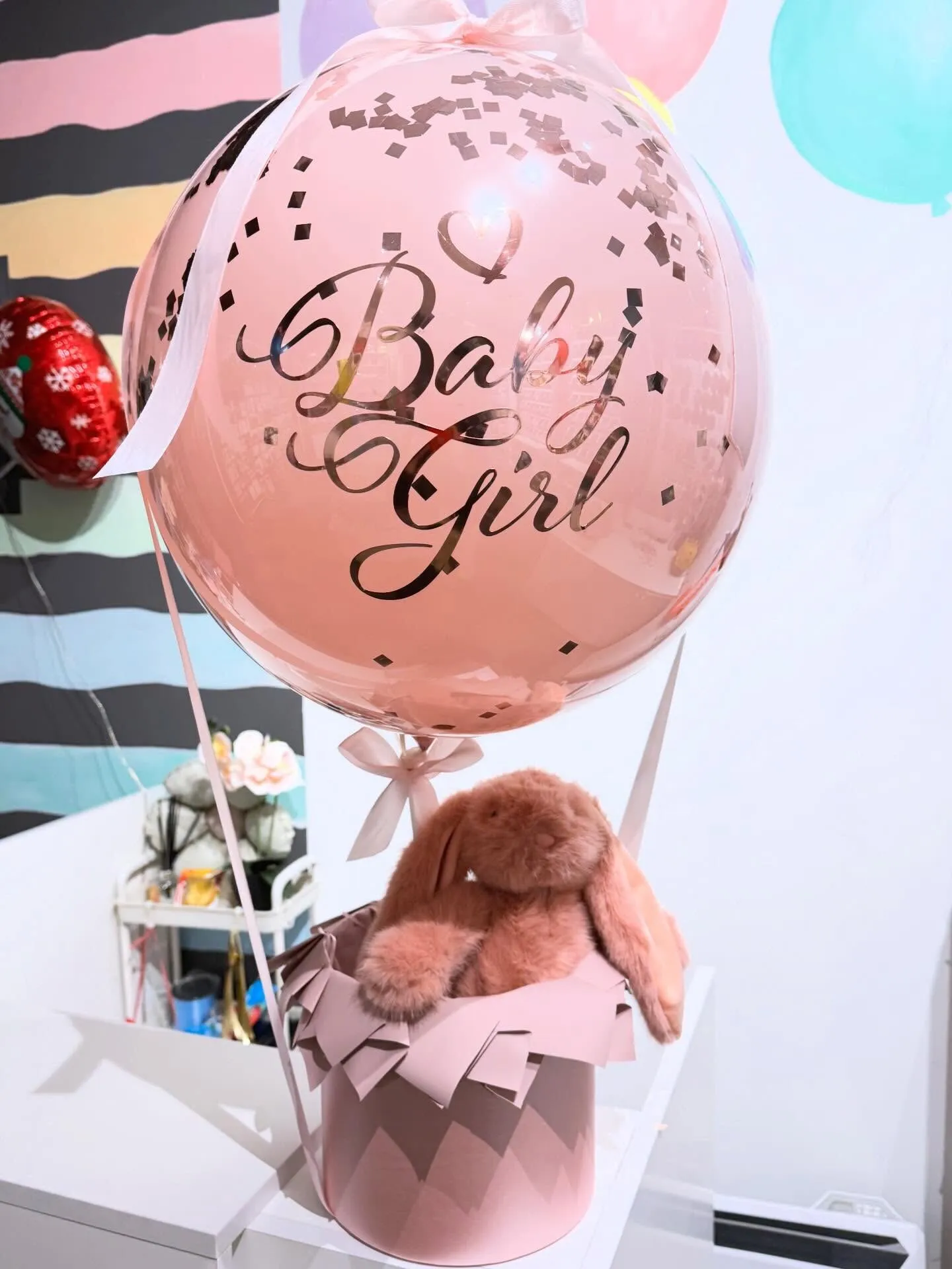 Рожева кулька з написом Baby Girl і мʼякою іграшкою в коробці