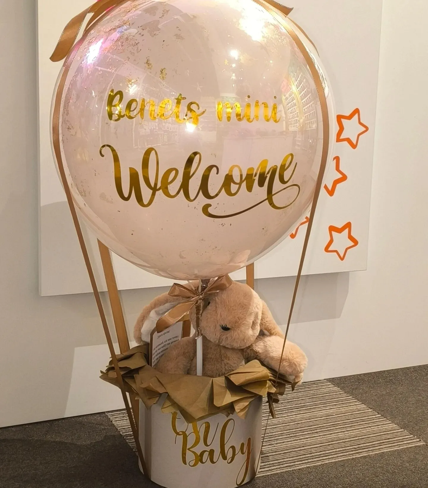 Кулька баблс із написом Welcome і мʼякою іграшкою в кошику